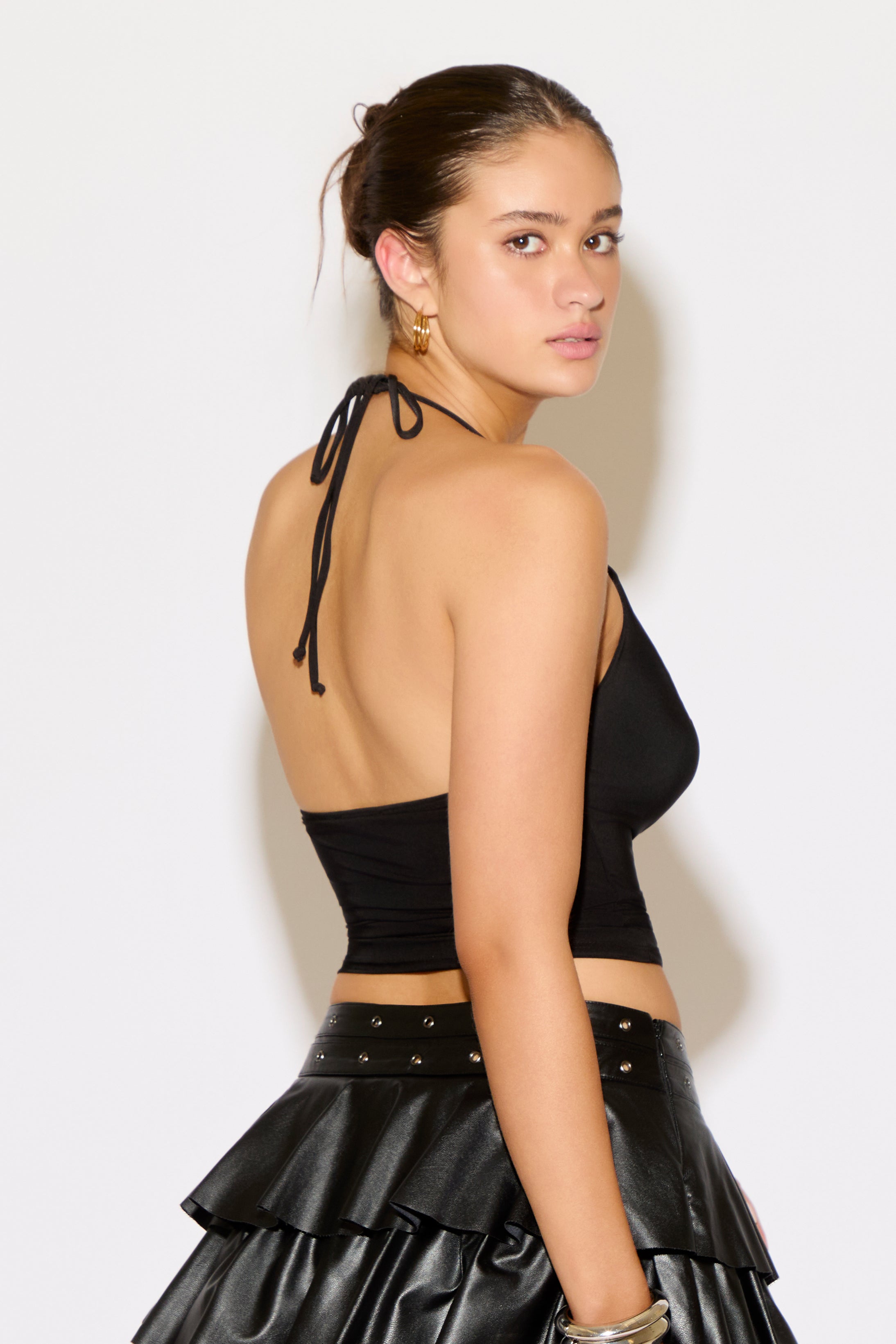 Woman wearing a black halter top and black skirt with a white background