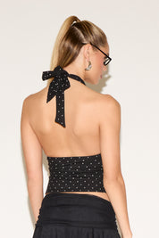 Woman wearing a black halter top with star patterns and a plain background
