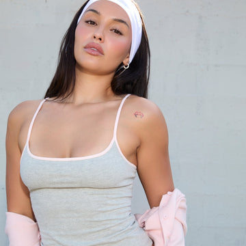 Model wearing a heather grey CONTRAST STRAPS SQUARE NECK CROP CAMI TOP with heather grey leggings in front of a grey wall.