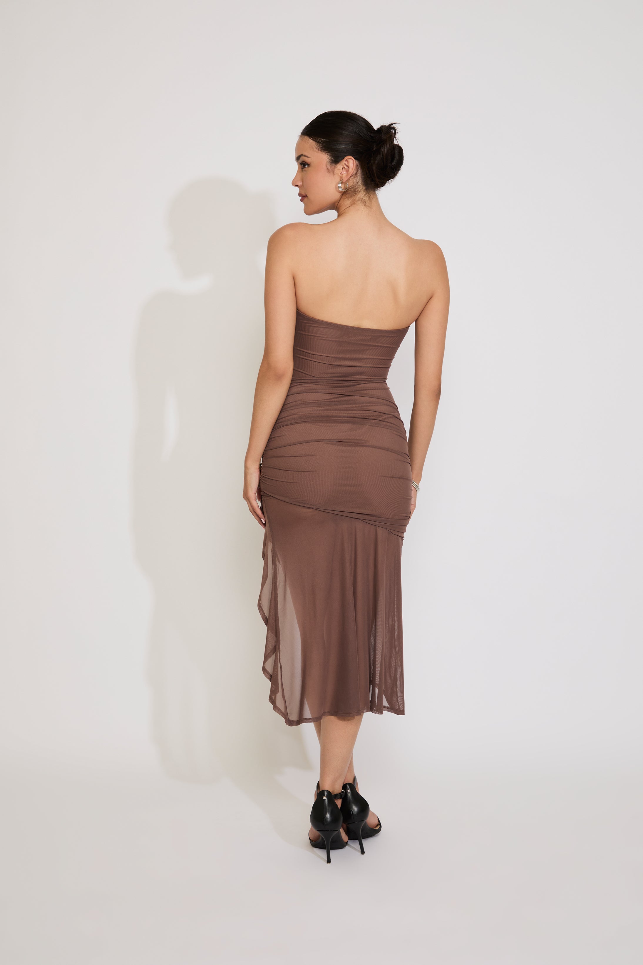 Woman wearing a brown strapless dress against a white background