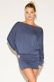 Woman wearing a blue off-shoulder dress against a white background