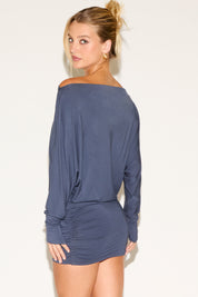 Woman wearing a blue off-shoulder dress against a white background