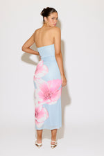 Woman wearing a strapless dress with pink floral pattern on a white background