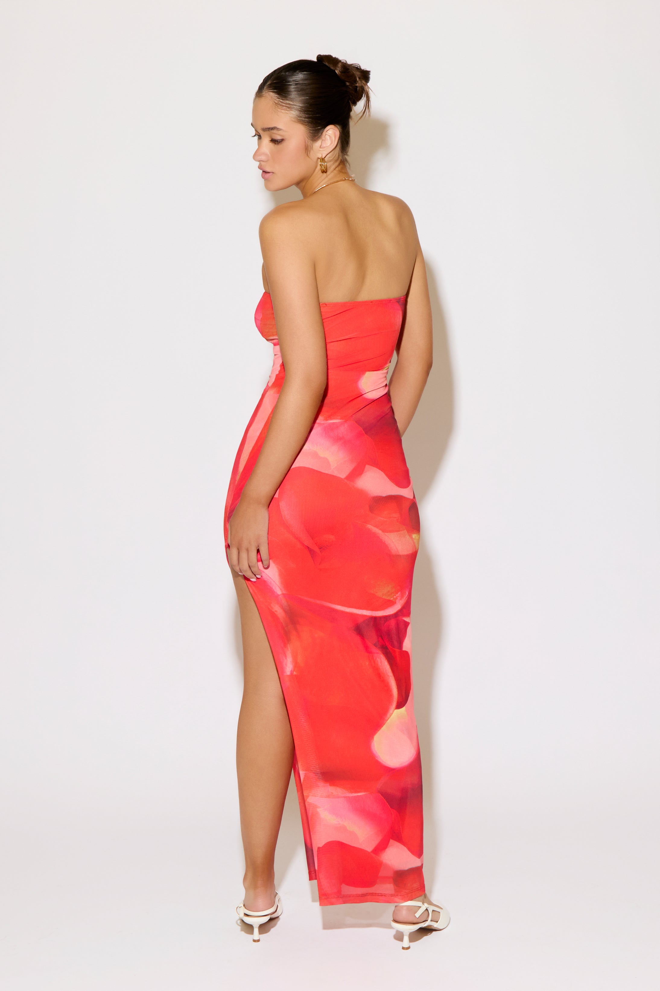 Woman wearing a strapless, colorful dress with a high slit on a white background