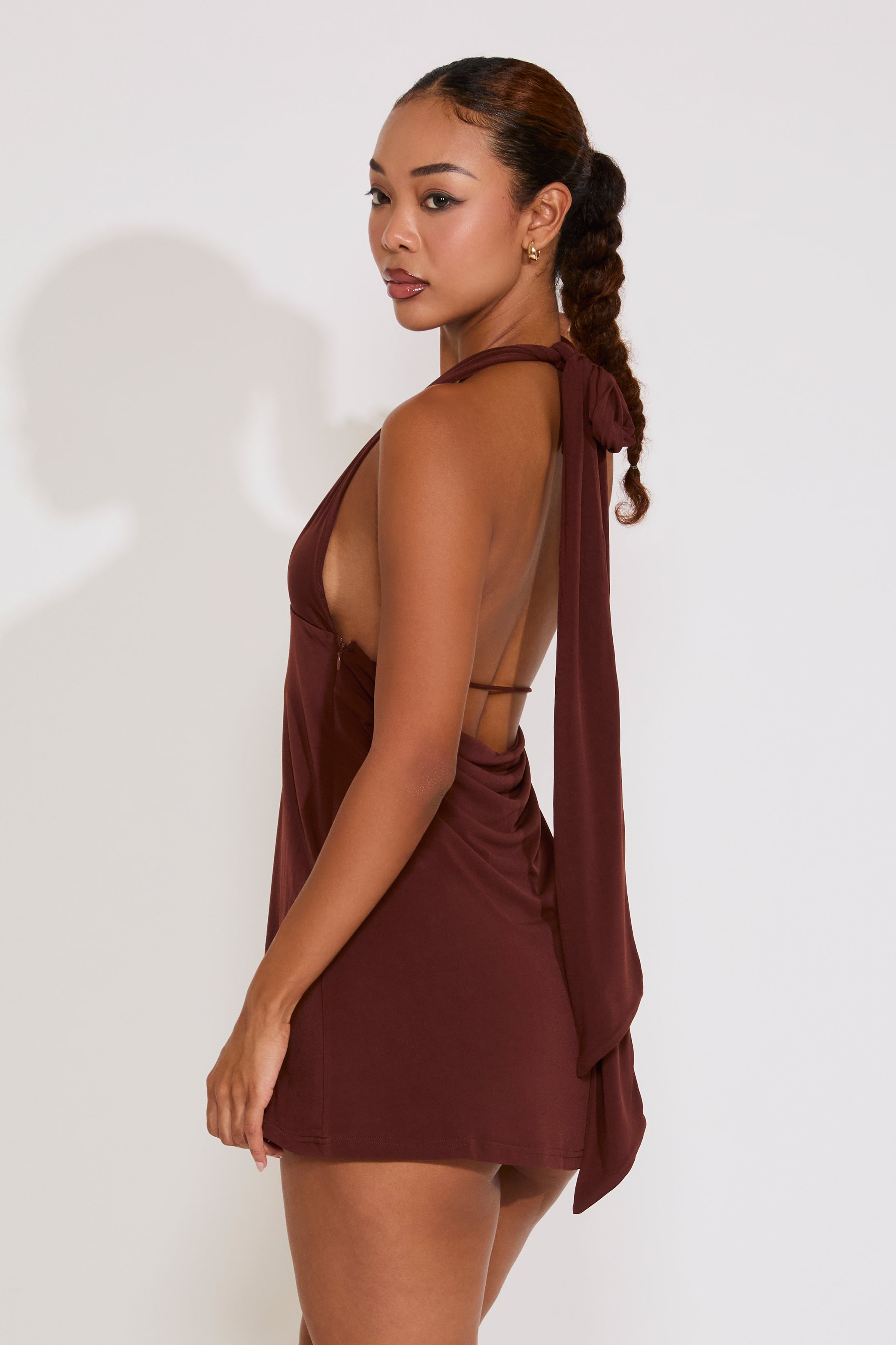 Woman wearing a brown halter neck dress with a white background