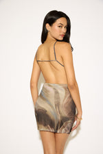 Woman wearing a patterned slip dress on a plain background