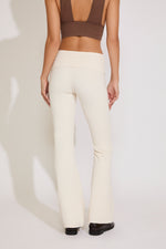 Person wearing beige pants and a brown top on a white background