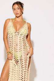 Woman wearing a beige crochet cover-up against a white background