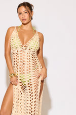 Woman wearing a beige crochet cover-up against a white background