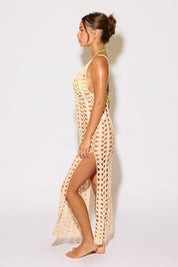 Woman wearing a long, patterned dress against a white background