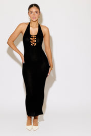 Woman wearing a black halter neck dress with gold accents on a white background