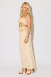 Model is wearing a natural crochet bandeau top and a matching crochet maxi skirt on a white background. 