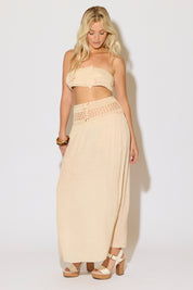 Model is wearing a natural crochet bandeau top and a matching crochet maxi skirt on a white background. 