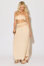 Model is wearing a natural crochet bandeau top and a matching crochet maxi skirt on a white background. 