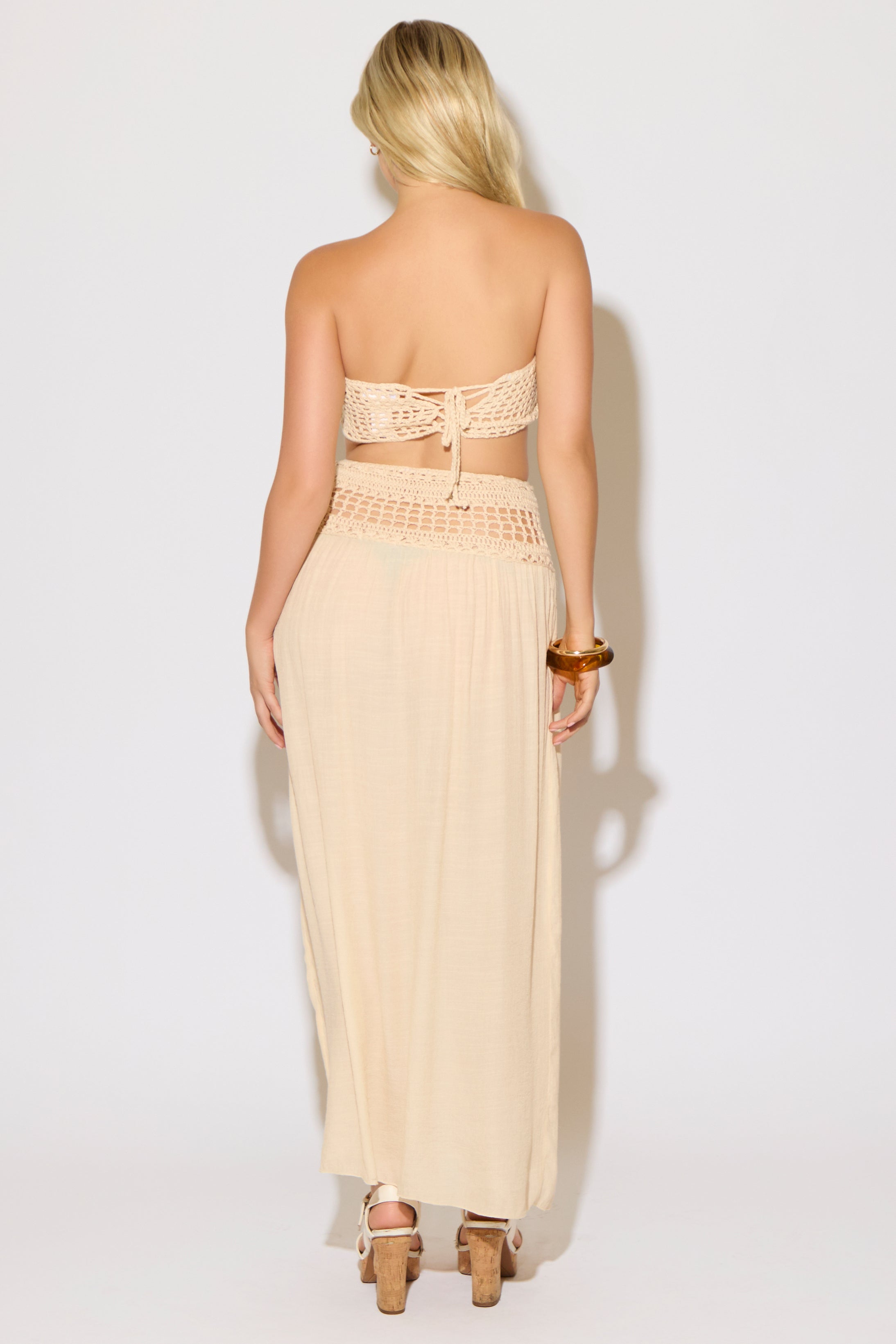 Model is wearing a natural crochet bandeau top and a matching crochet maxi skirt on a white background. 