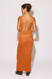 Woman wearing a long orange dress with a sheer back on a white background