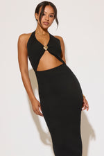 Woman wearing a black halter neck dress with cut-out design on a white background