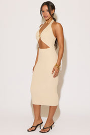 Woman wearing a beige halter neck dress with cut-out design on a white background