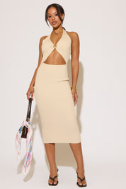 Woman wearing a beige dress holding a colorful bag against a white background