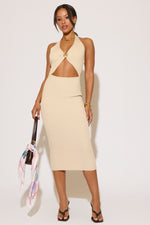 Woman wearing a beige dress holding a colorful bag against a white background