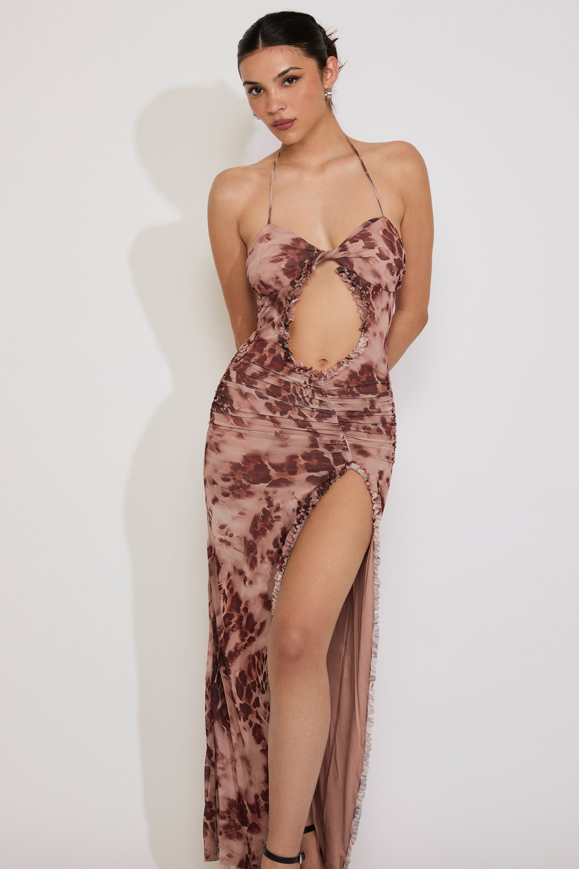 Woman wearing a patterned dress with a high slit on a white background