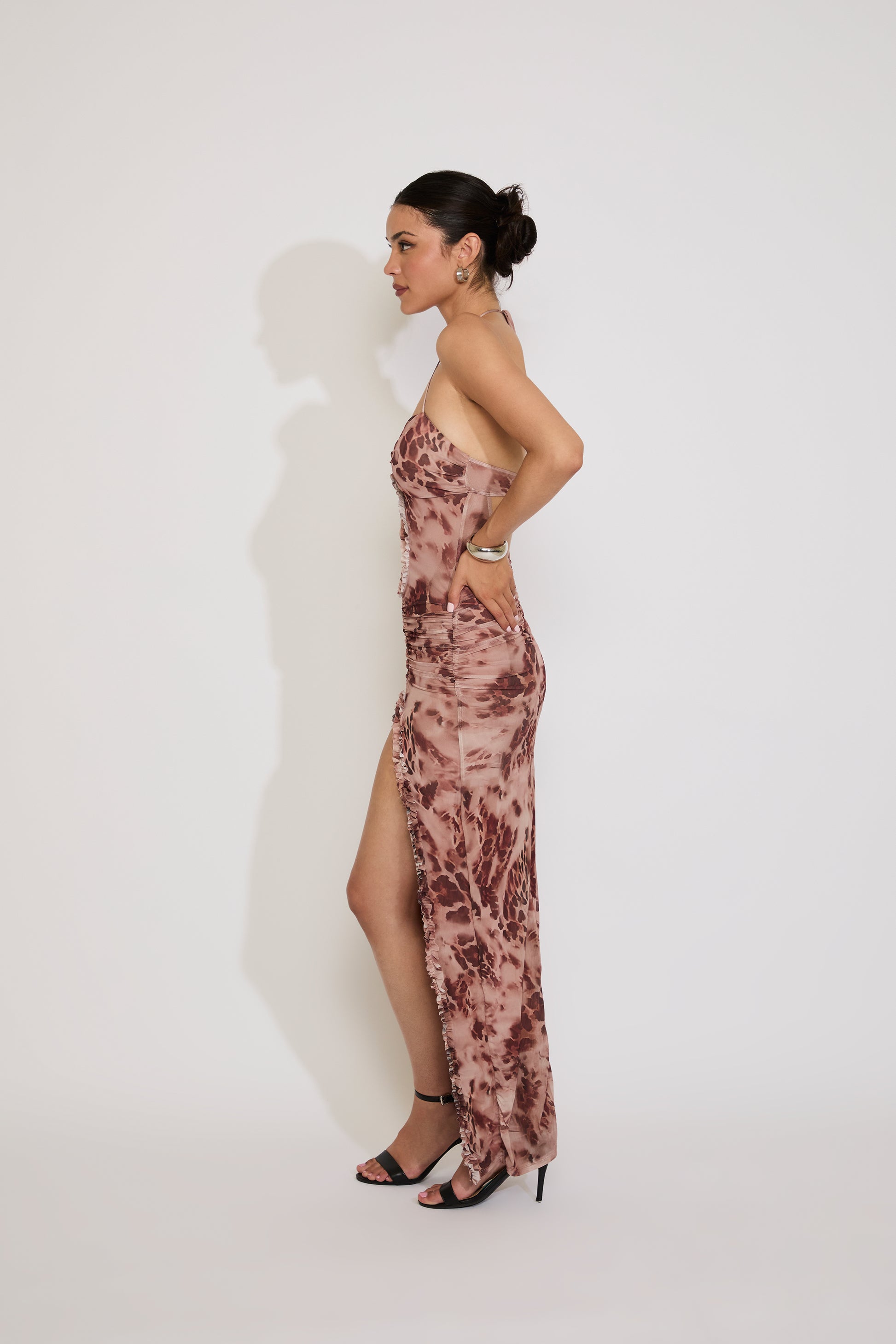 Woman wearing a floral strapless gown with a high slit on a white background