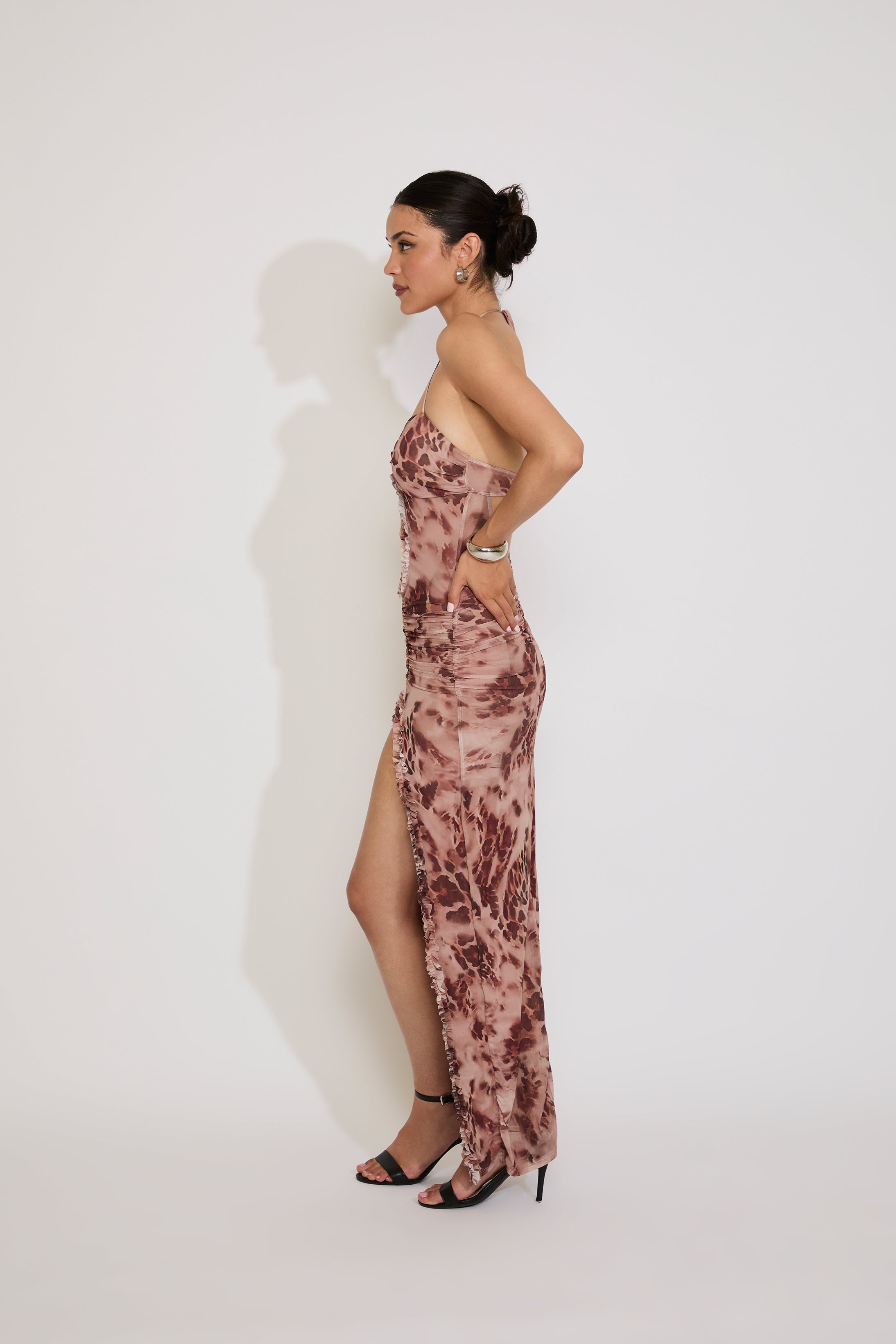 Woman wearing a floral strapless gown with a high slit on a white background