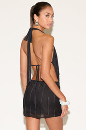 Woman wearing a black open-back dress against a white background