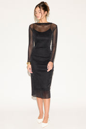 Woman wearing a black sheer dress with long sleeves on a white background