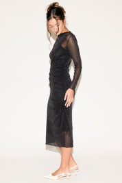 Woman wearing a black sheer dress with long sleeves on a white background