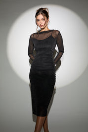 Woman wearing a black sheer dress with long sleeves on a white background