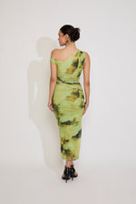 Woman wearing a green one-shoulder dress with abstract pattern on a white background
