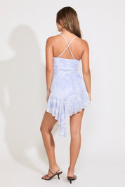 Model is wearing a blue cross back tie dye ruffled mini dress on a white background.