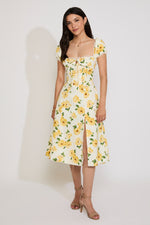 Woman wearing a yellow floral dress against a white background