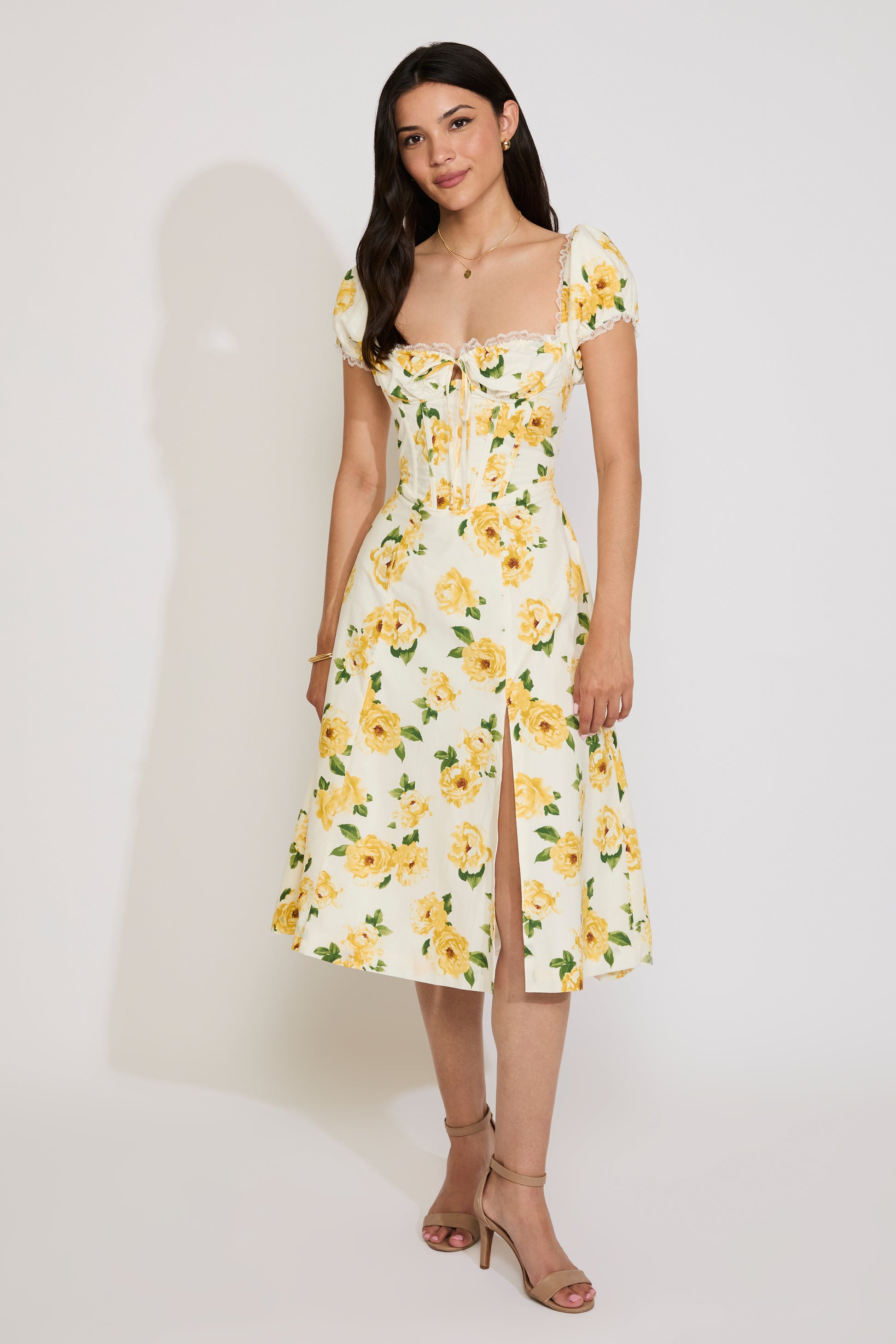 Woman wearing a yellow floral dress against a white background