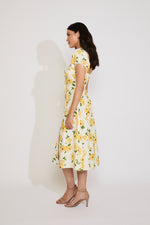 Woman wearing a yellow floral dress against a white background