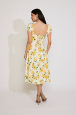 Woman wearing a yellow floral dress against a white background