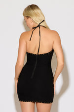 Model is wearing a black halter neck, western design bodycon mini dress on a white background. 