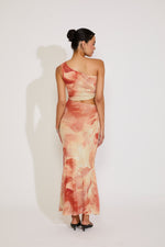 Woman wearing a one-shoulder dress with a watercolor pattern on a white background