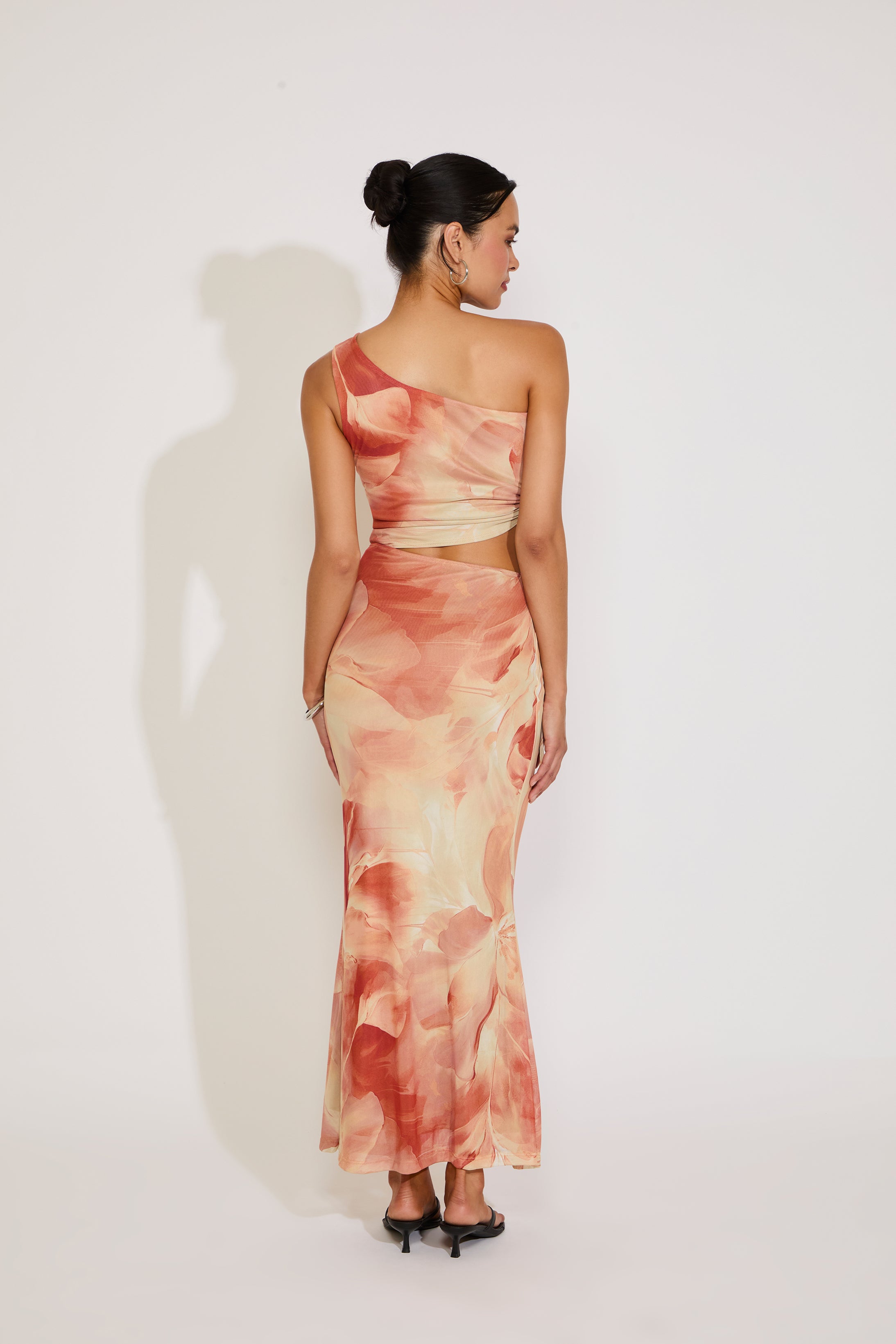 Woman wearing a one-shoulder dress with a watercolor pattern on a white background