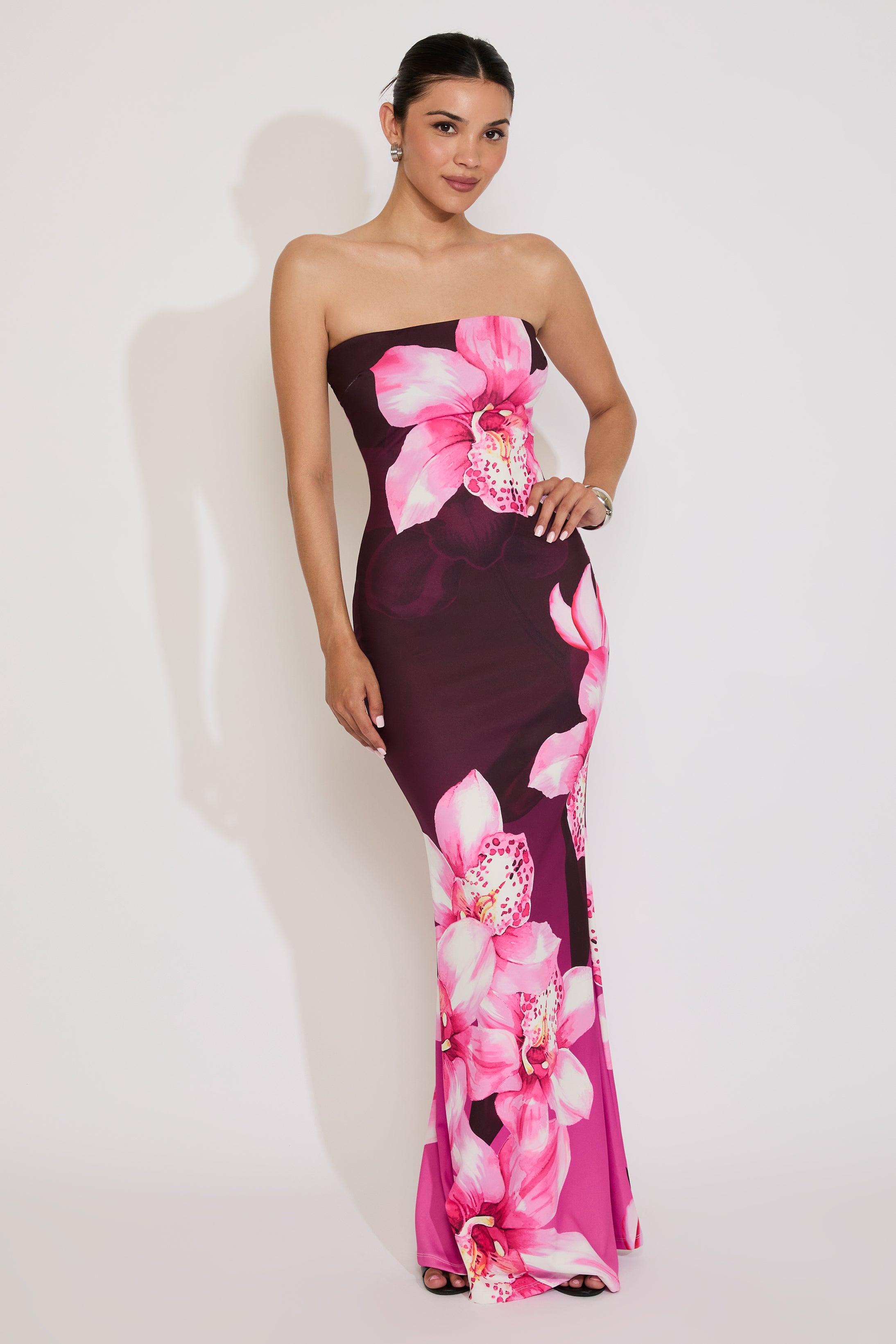 Woman wearing a strapless dress with pink floral design on a white background