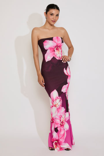 Woman wearing a strapless dress with pink floral design on a white background