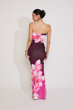 Woman wearing a strapless dress with pink floral pattern on a white background