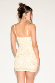 Woman wearing a beige lace dress against a white background