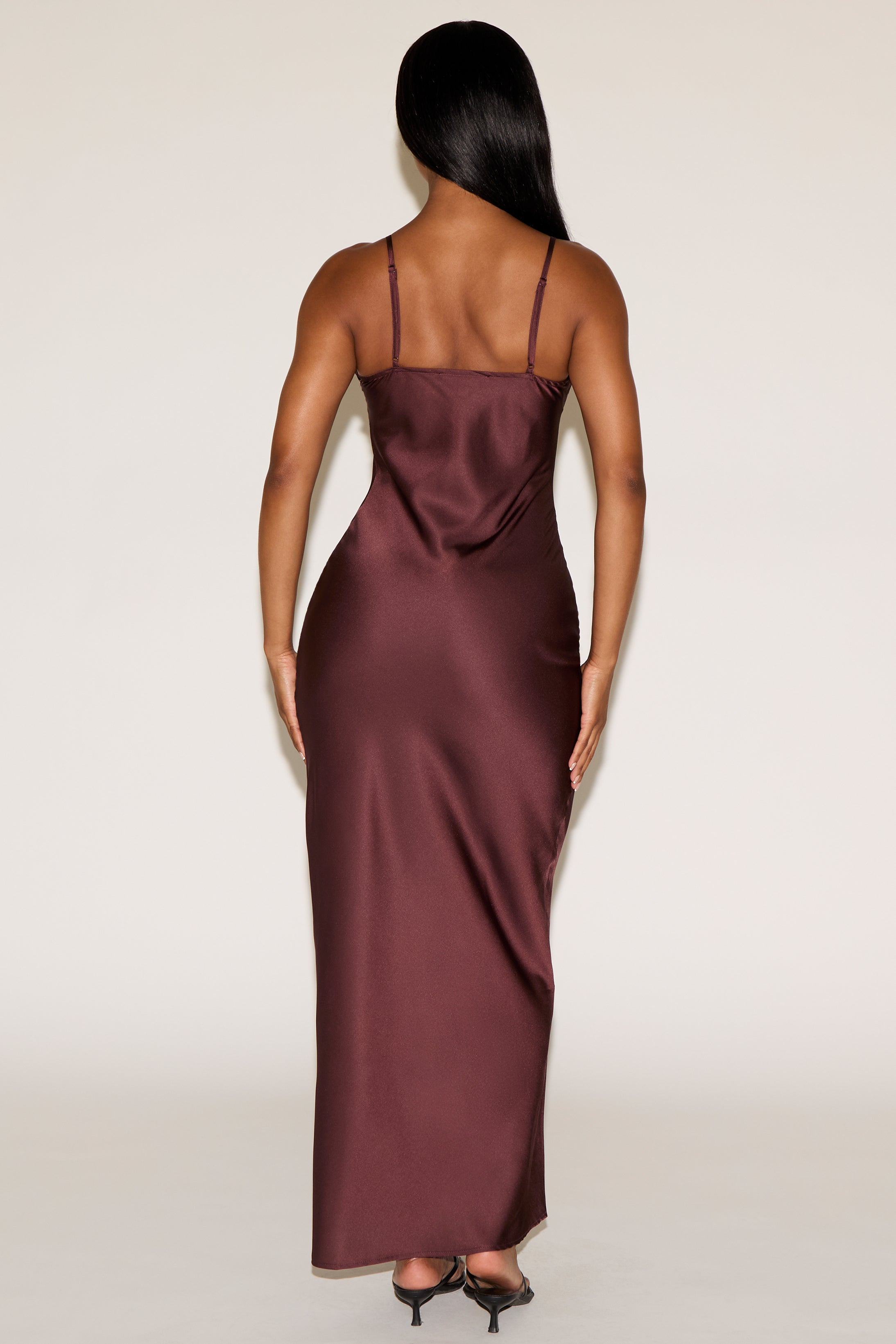 Woman wearing a burgundy satin dress against a white background