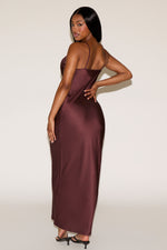Woman wearing a burgundy satin dress against a white background