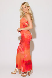 Model is wearing a orange strapless mesh printed ruched maxi dress on a white background.