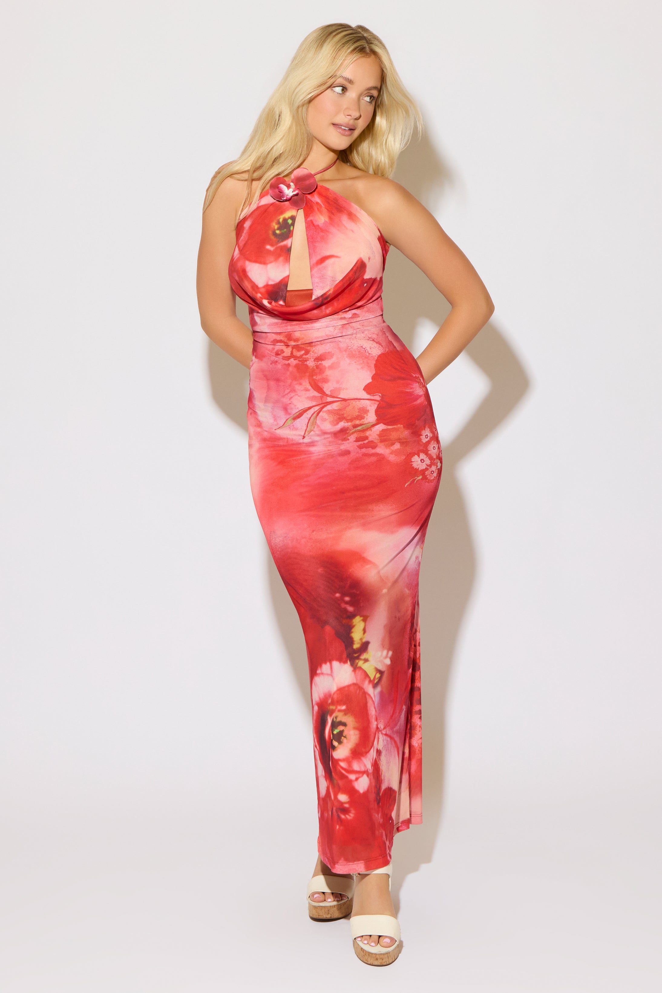 Model is wearing a orange tie neck floral print cowl keyhole maxi dress on a white background. 