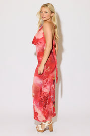 Model is wearing a orange tie neck floral print cowl keyhole maxi dress on a white background. 