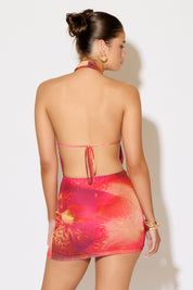 Woman wearing a colorful halter top and skirt set against a white background